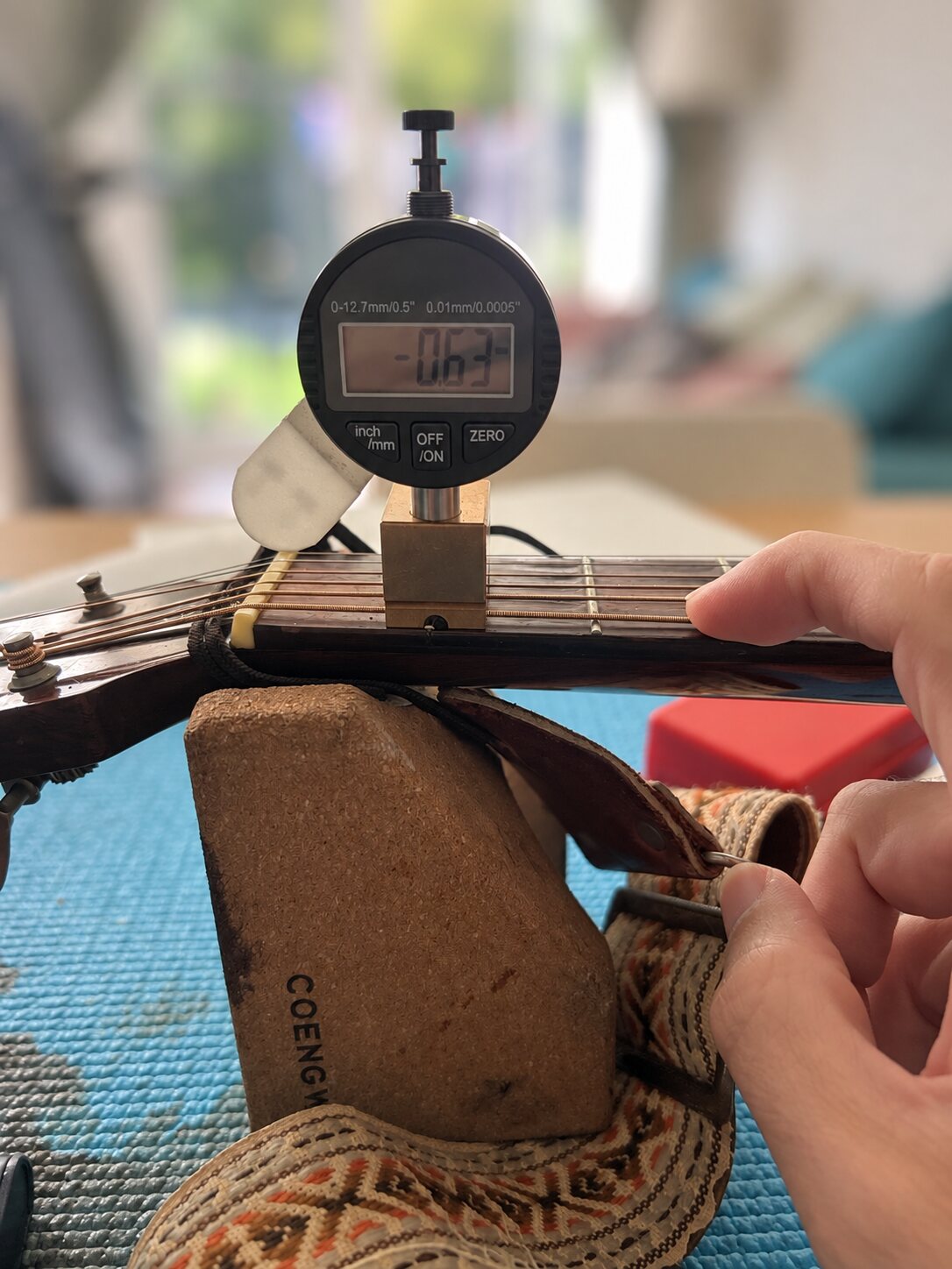 Digital neck relief gauge measuring an acoustic guitar in Nottingham