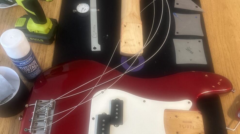 Red bass guitar undergoing a professional setup in Nottingham using specialist tools