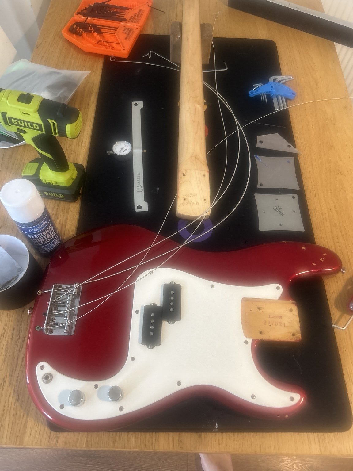 Red bass guitar undergoing a professional setup in Nottingham using specialist tools