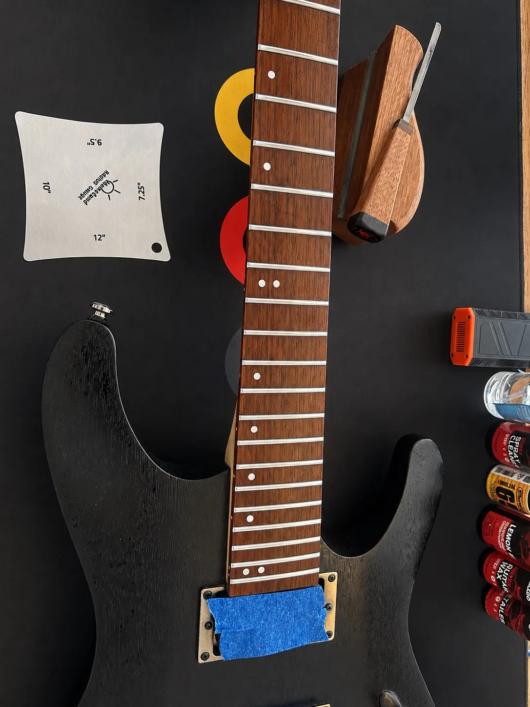 Polished frets on a black electric guitar during workshop fretwork