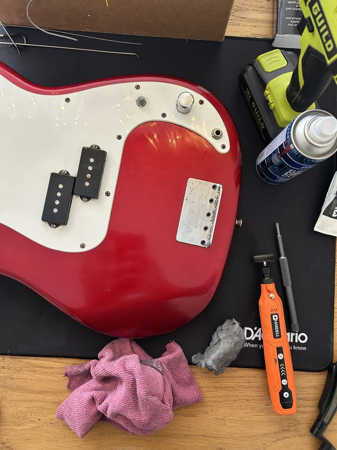 Red bass guitar on a workbench during a professional setup and repair