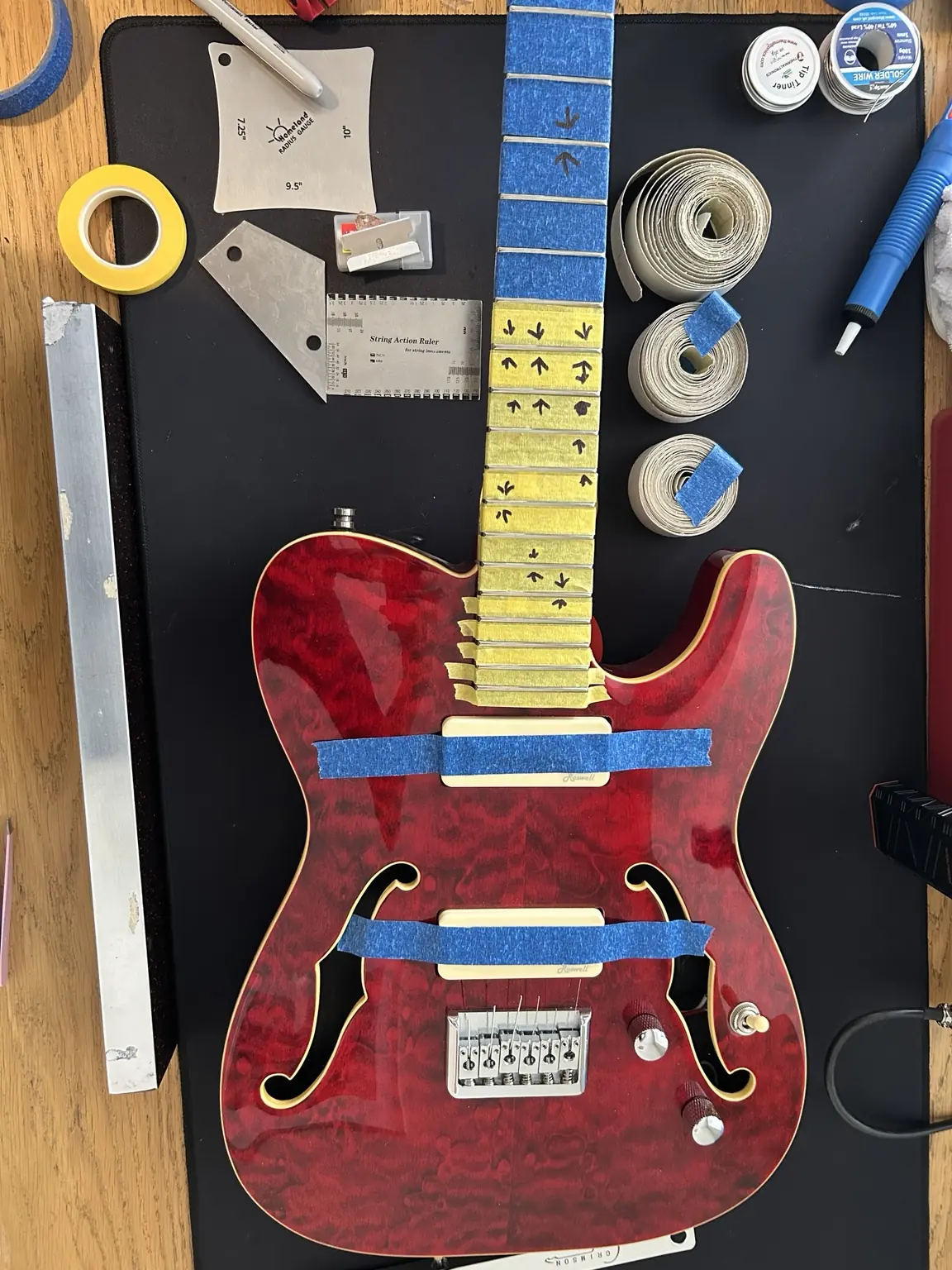 Red semi-hollow guitar prepared for professional fret levelling