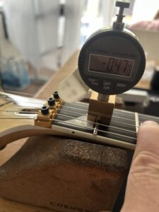 Digital dial indicator measuring string clearance at a guitar nut